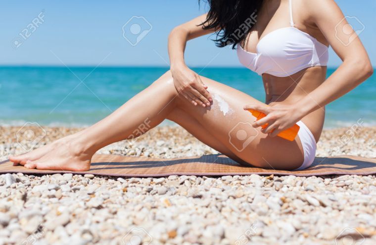 femme appliquant crème solaire à la plage